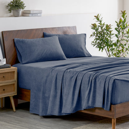 Indigo bedding set on a bed with a wooden headboard and plant in the background