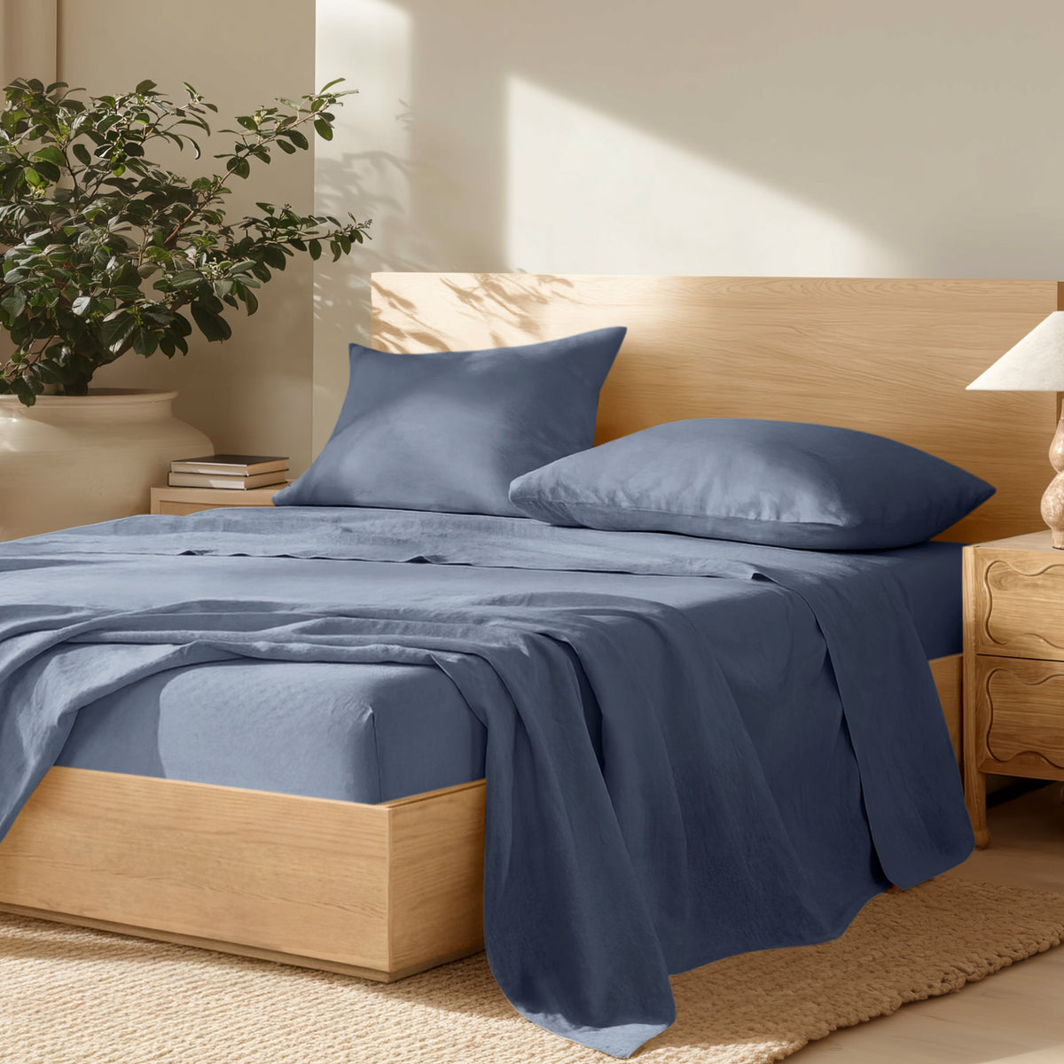 Bedroom with wooden bed frame, linen bedding, and a plant on a nightstand.