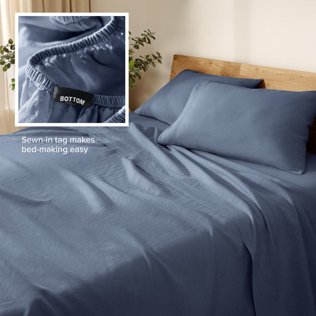 Linen bed sheets and pillowcases on a wooden bed with a plant in the background