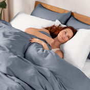 Woman lying in bed under duvet cover.