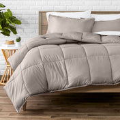 Comforter set on a bed with a white brick wall and plant in the background