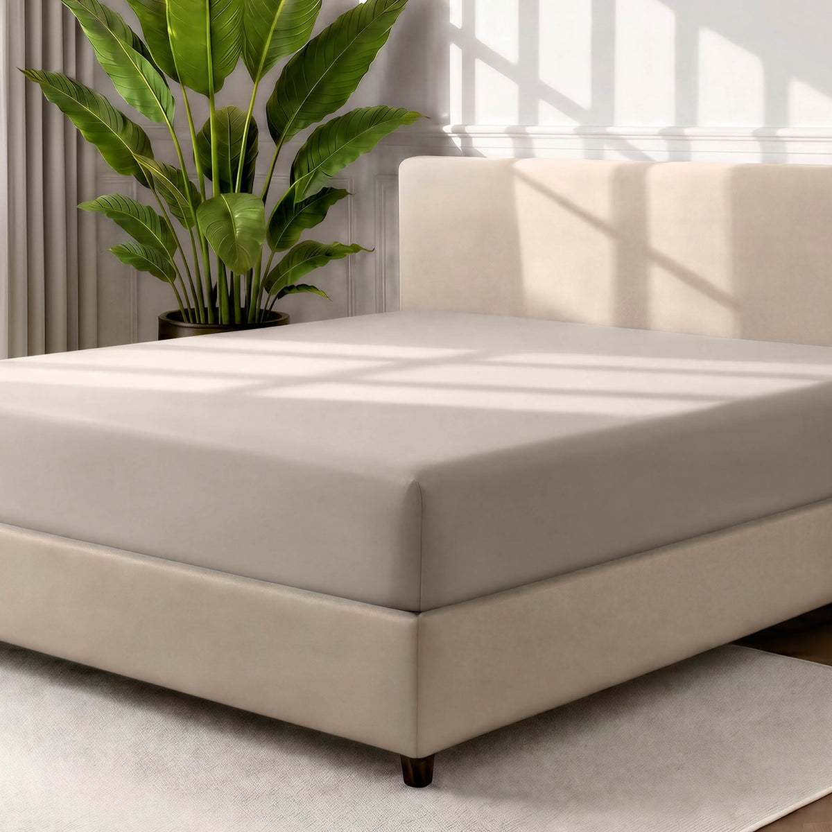 Man adjusting fitted sheet on a bed with white pillows.