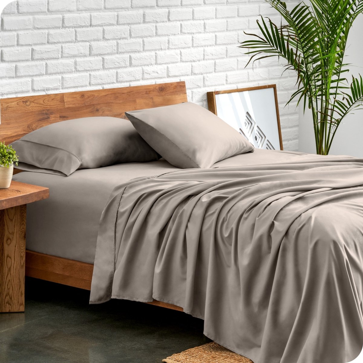 Bed with microfiber sheets against a white brick wall