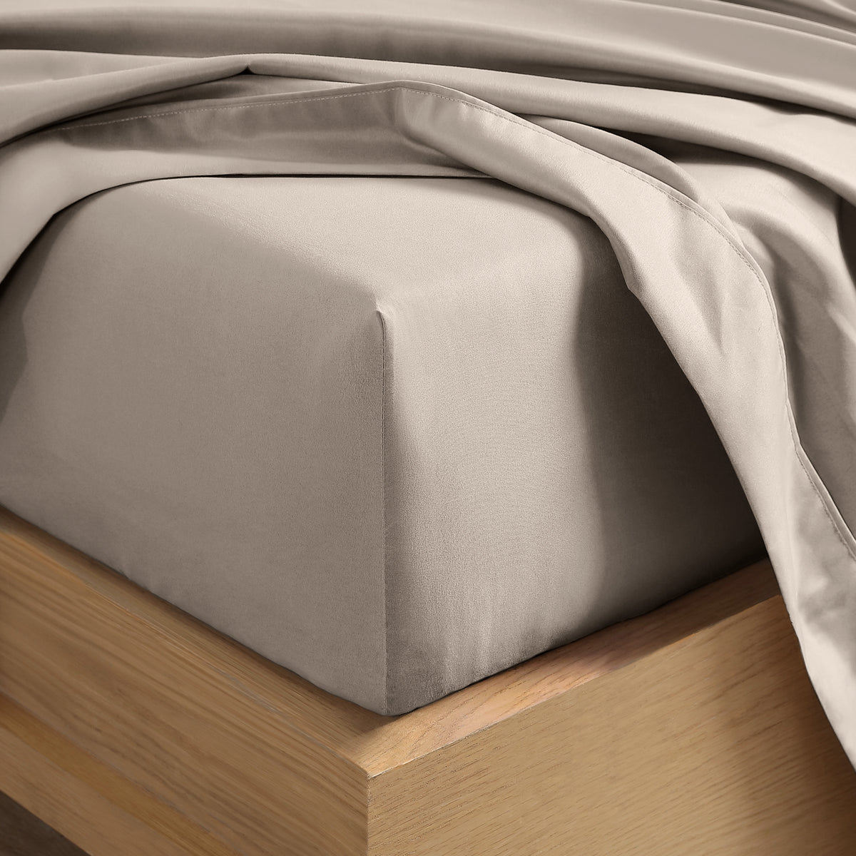 Close up of the corner of a mattress with a fitted sheet and flat sheet on it