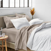 Sheets and a duvet cover on a bed in a bright bedroom