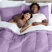 A couple is lying in bed with a comforter and sheets over them