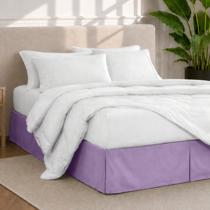 A modern bedroom with a bed skirt, comforter and sheets on the bed