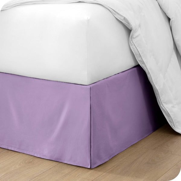 The corner of a bed with a bed skirt and comforter on it