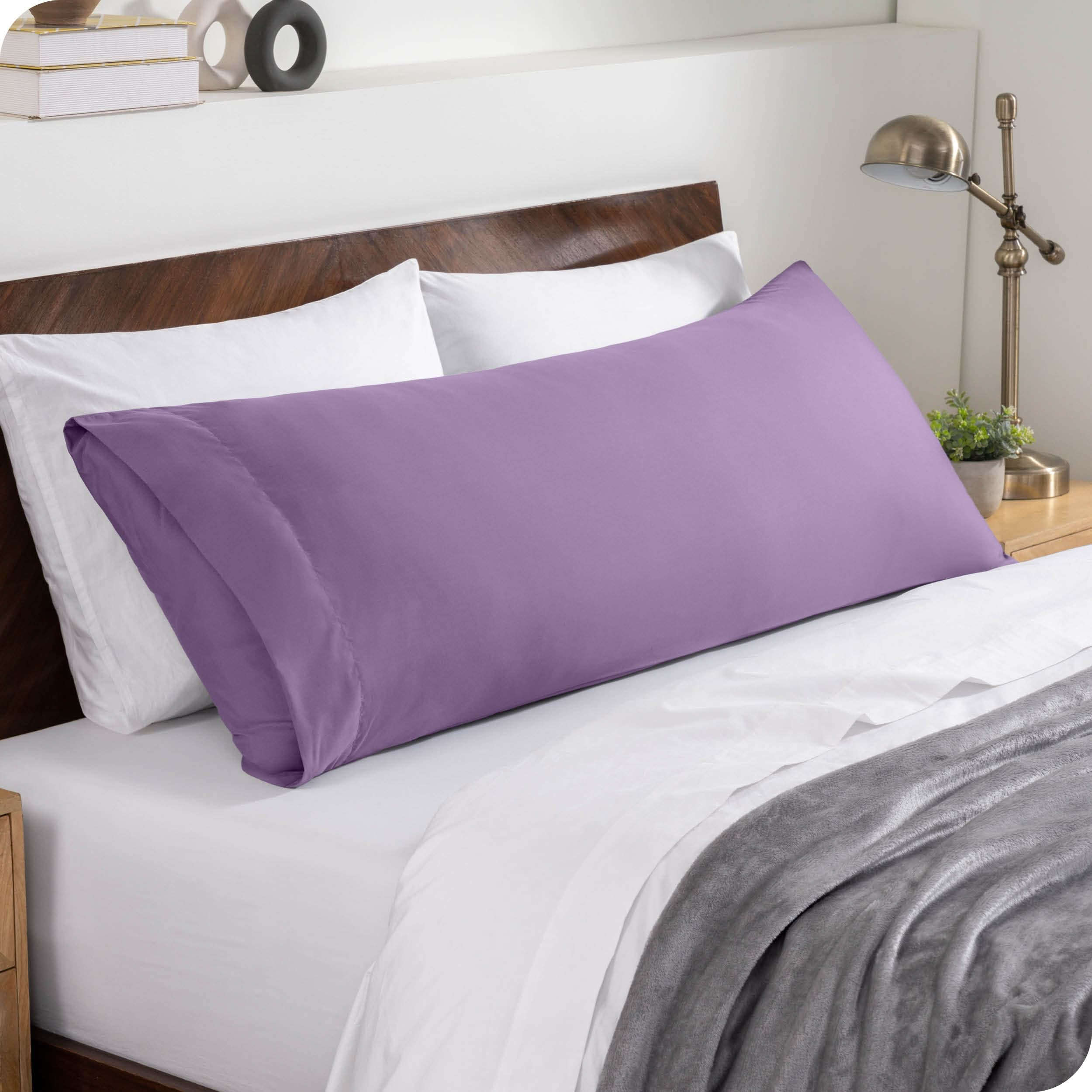 A body pillowcase on a pillow set against a headboard