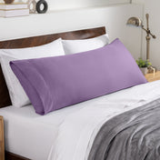 Bed sheets and pillows on a neatly made bed with a wooden headboard.