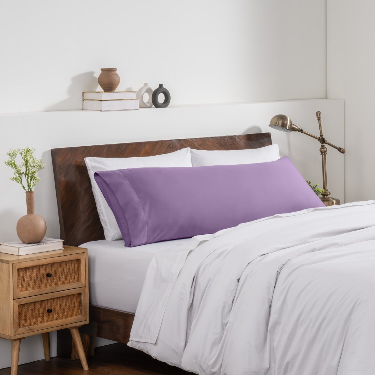 Bedroom with a wooden headboard and white bedding, featuring a nightstand and decorative items.