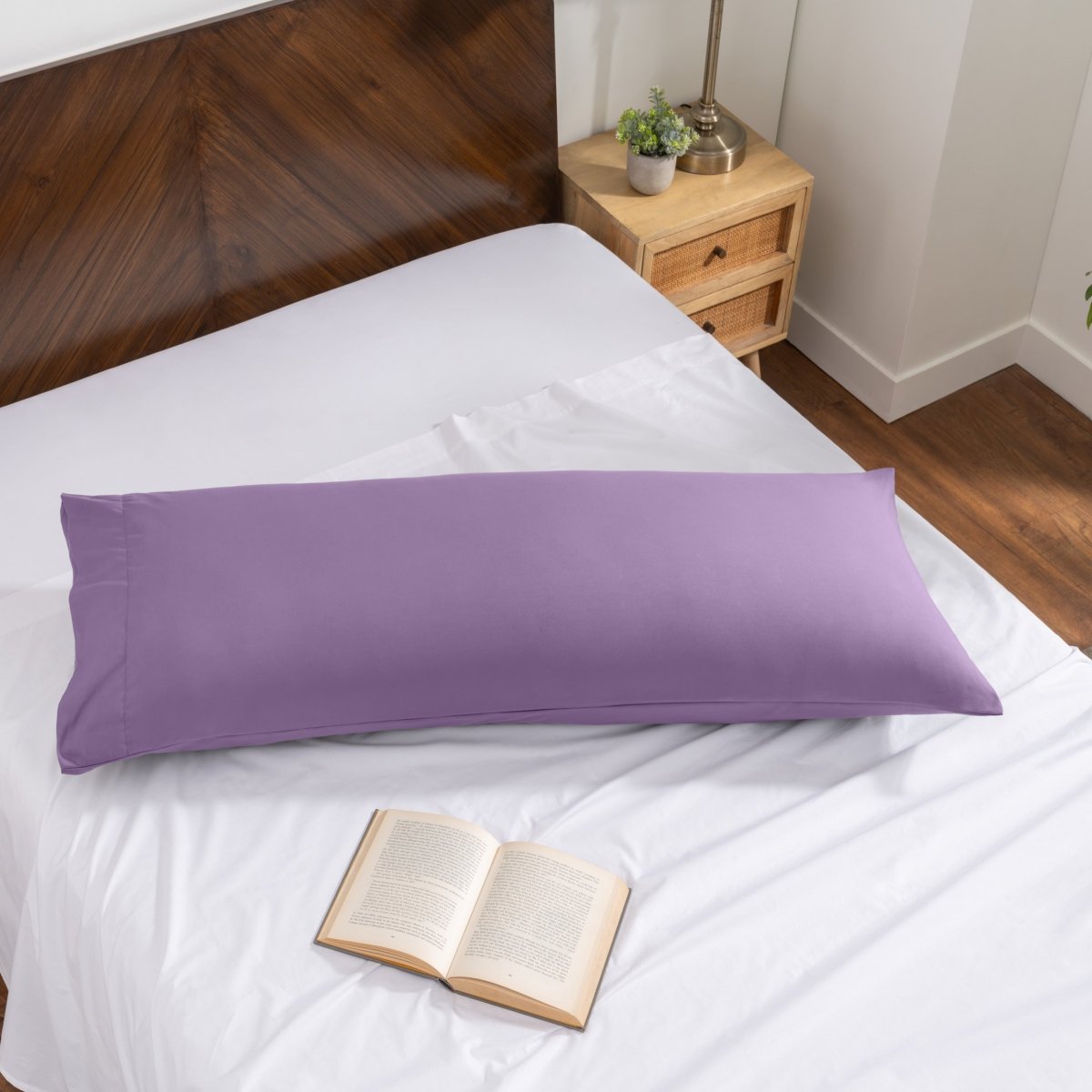 Pillowcase on a body pillow with a wooden headboard and plant in the background