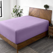 A diagonal view of a bed with just a fitted sheet on it