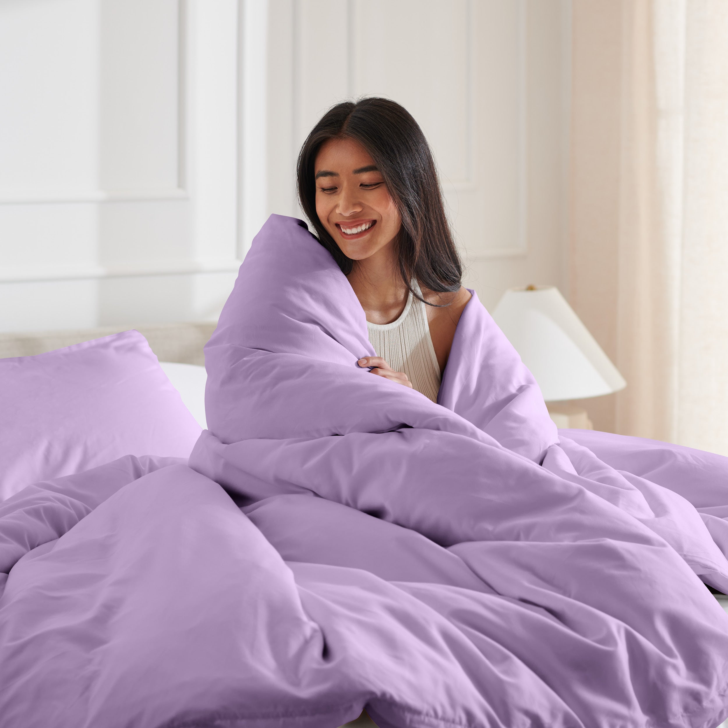 Woman smiling under duvet cover set in a bedroom setting