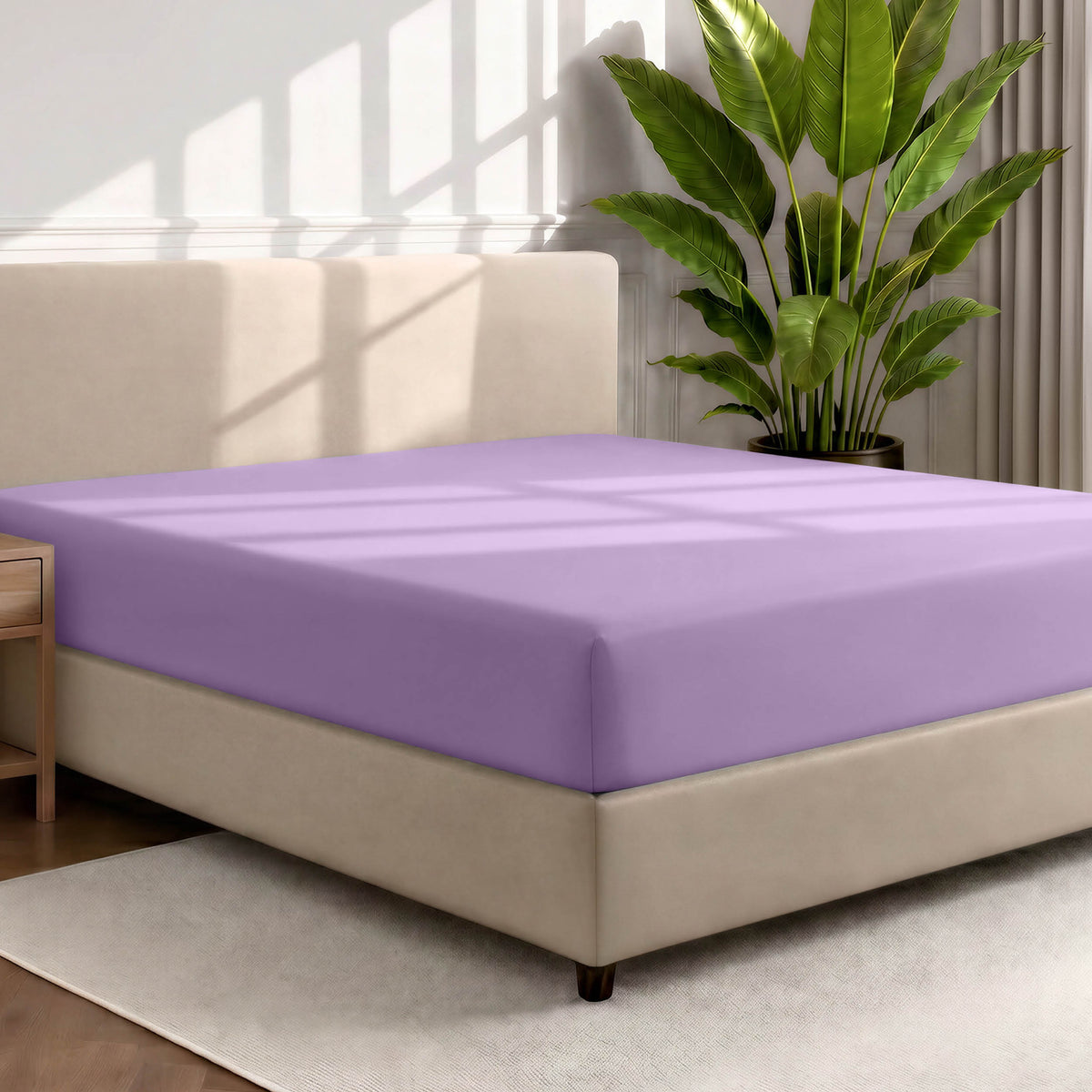 Bed with a fitted sheet in a room with a large plant and rug