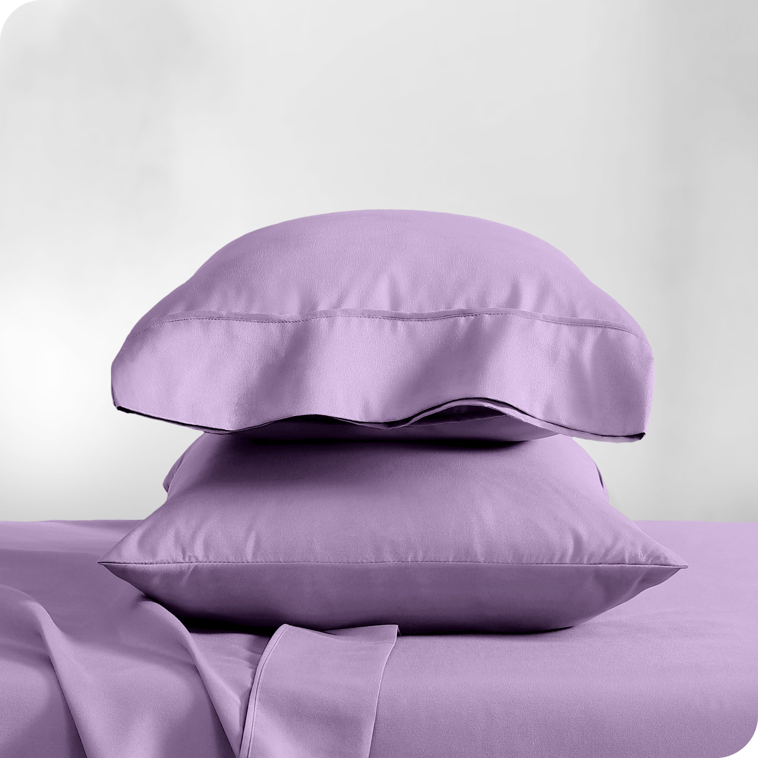 Two pillowcases on pillows stacked on a bed with matching sheets