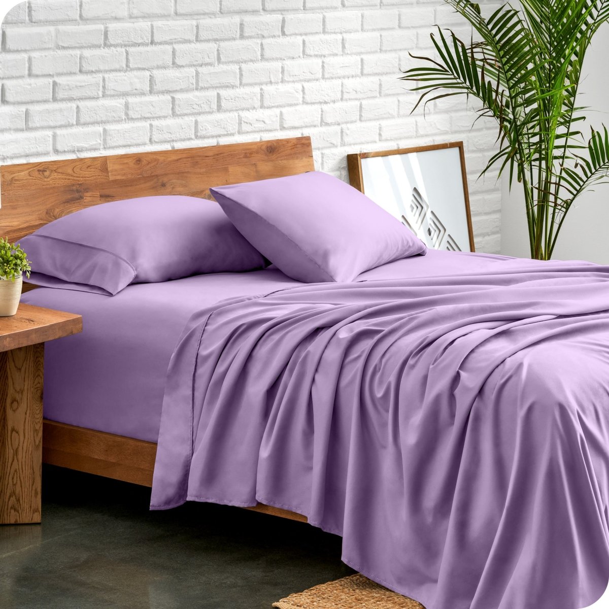 Bed with microfiber sheets against a white brick wall