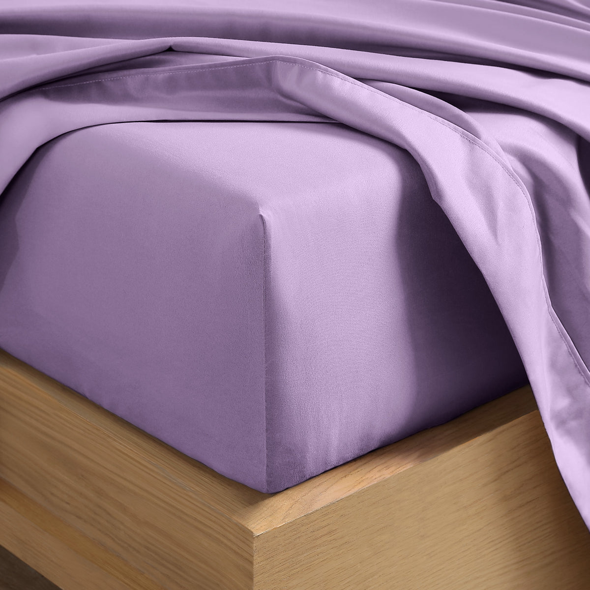 Close up of the corner of a mattress with a fitted sheet and flat sheet on it
