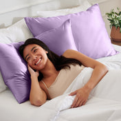 Woman lying on a bed with satin pillows and white bedding