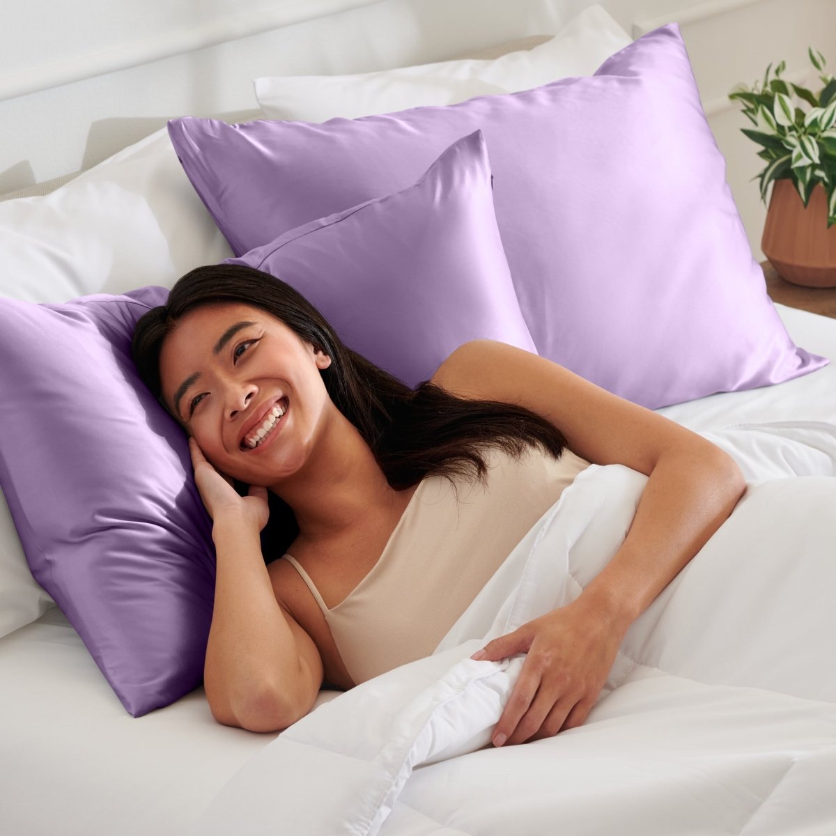 Woman lying on a bed with satin pillows and white bedding