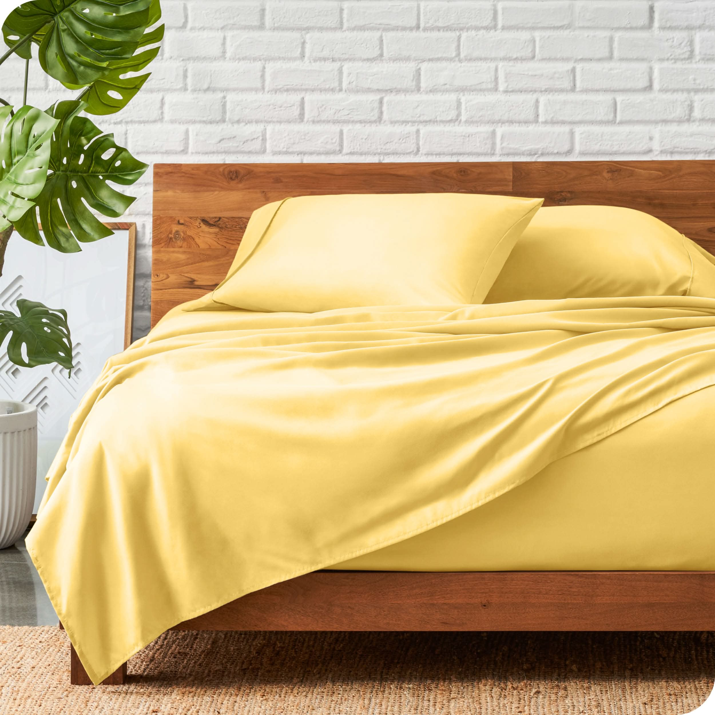 A wooden bed frame with a microfiber sheet set on the mattress.