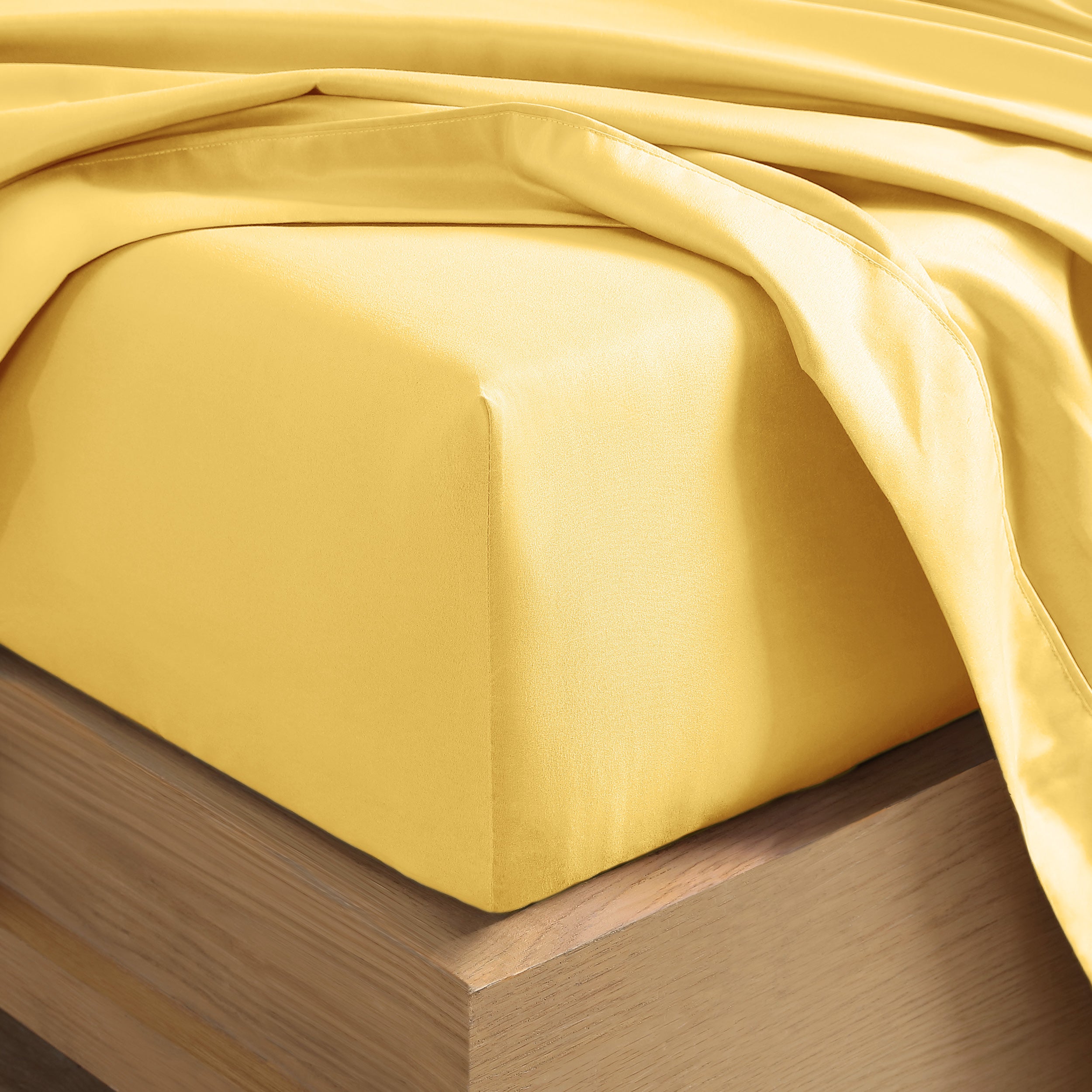 Close up of the corner of a mattress with a fitted sheet and flat sheet on it