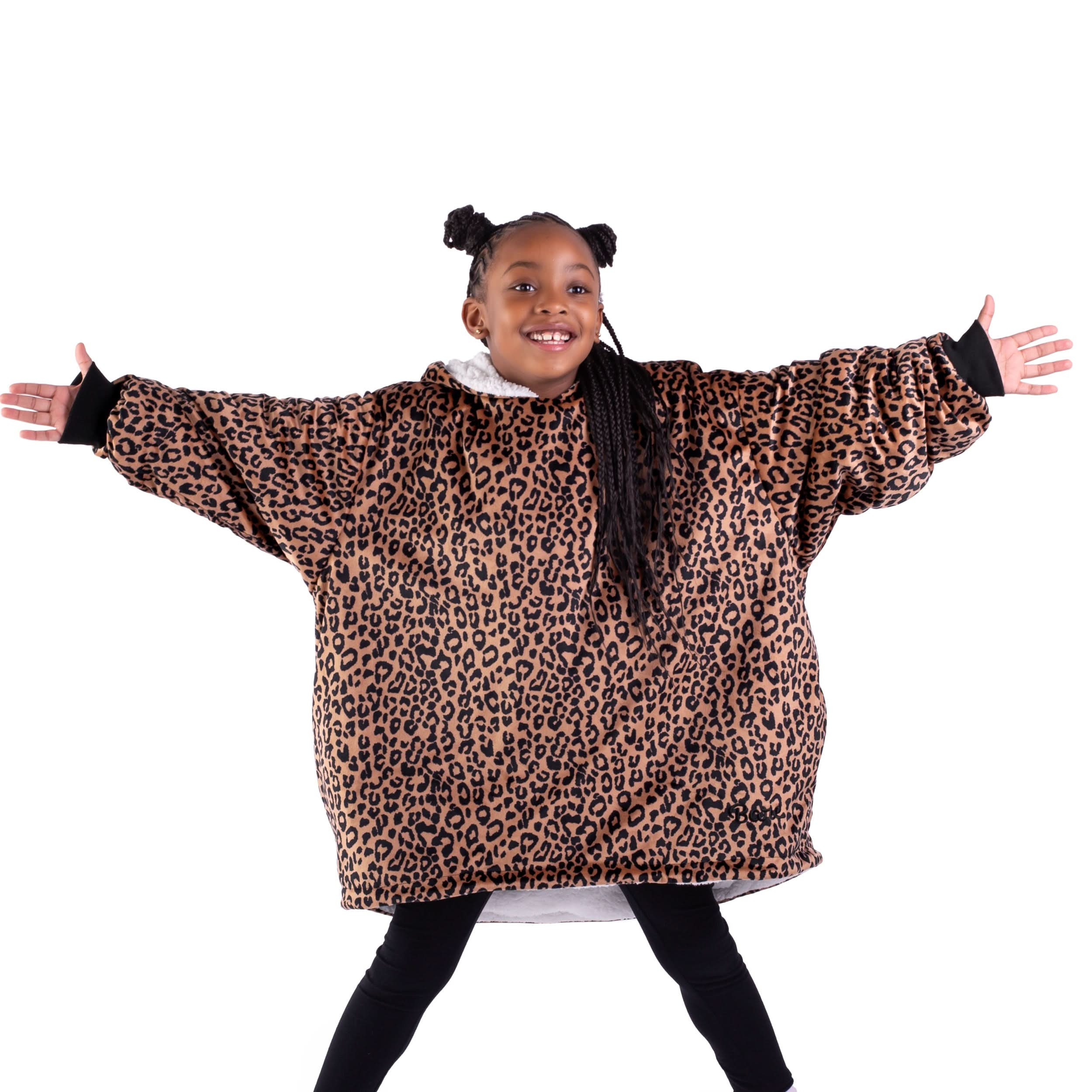 A girl standing with her arms stretched out while wearing a wearable blanket