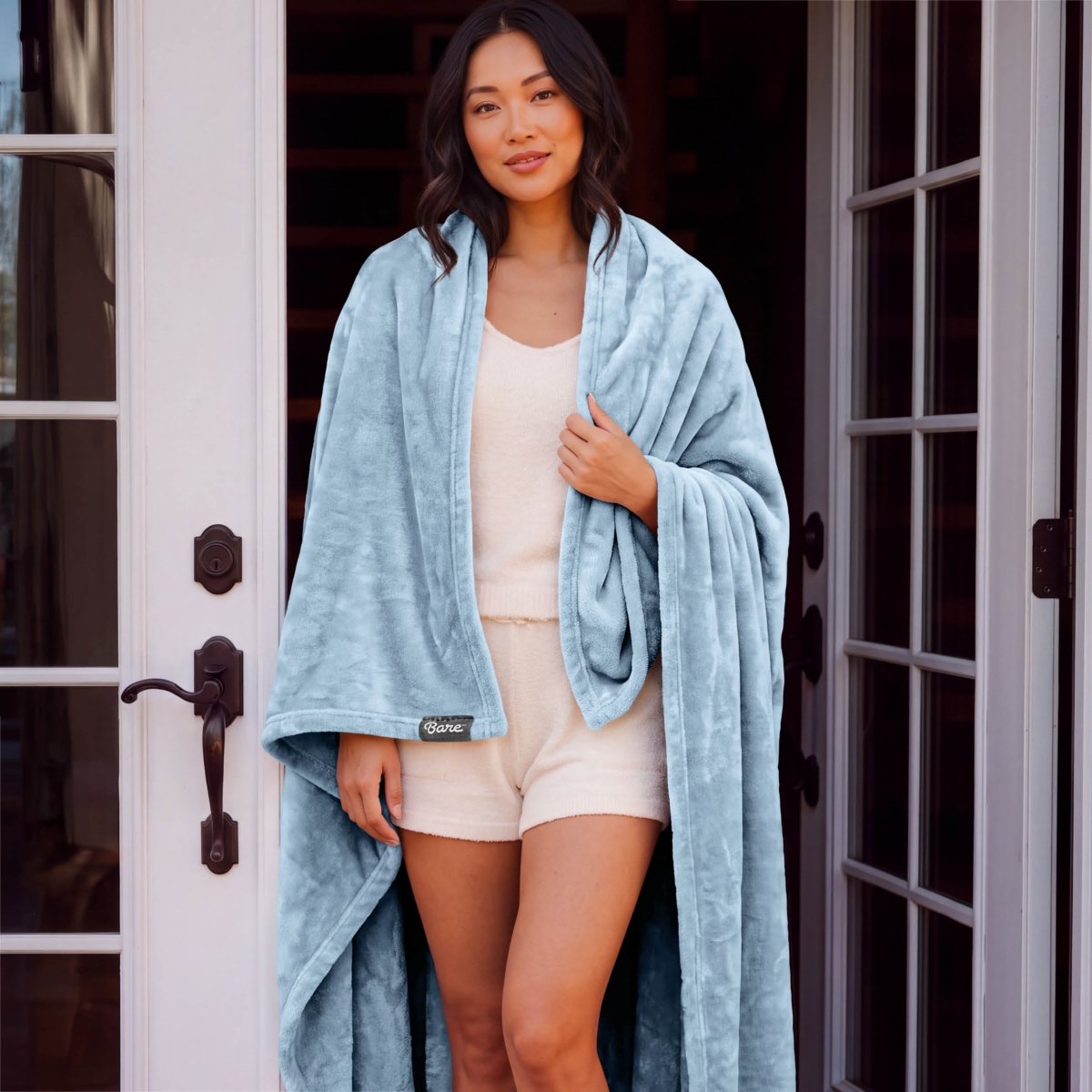 A woman standing with a microplush blanket wrapped around her
