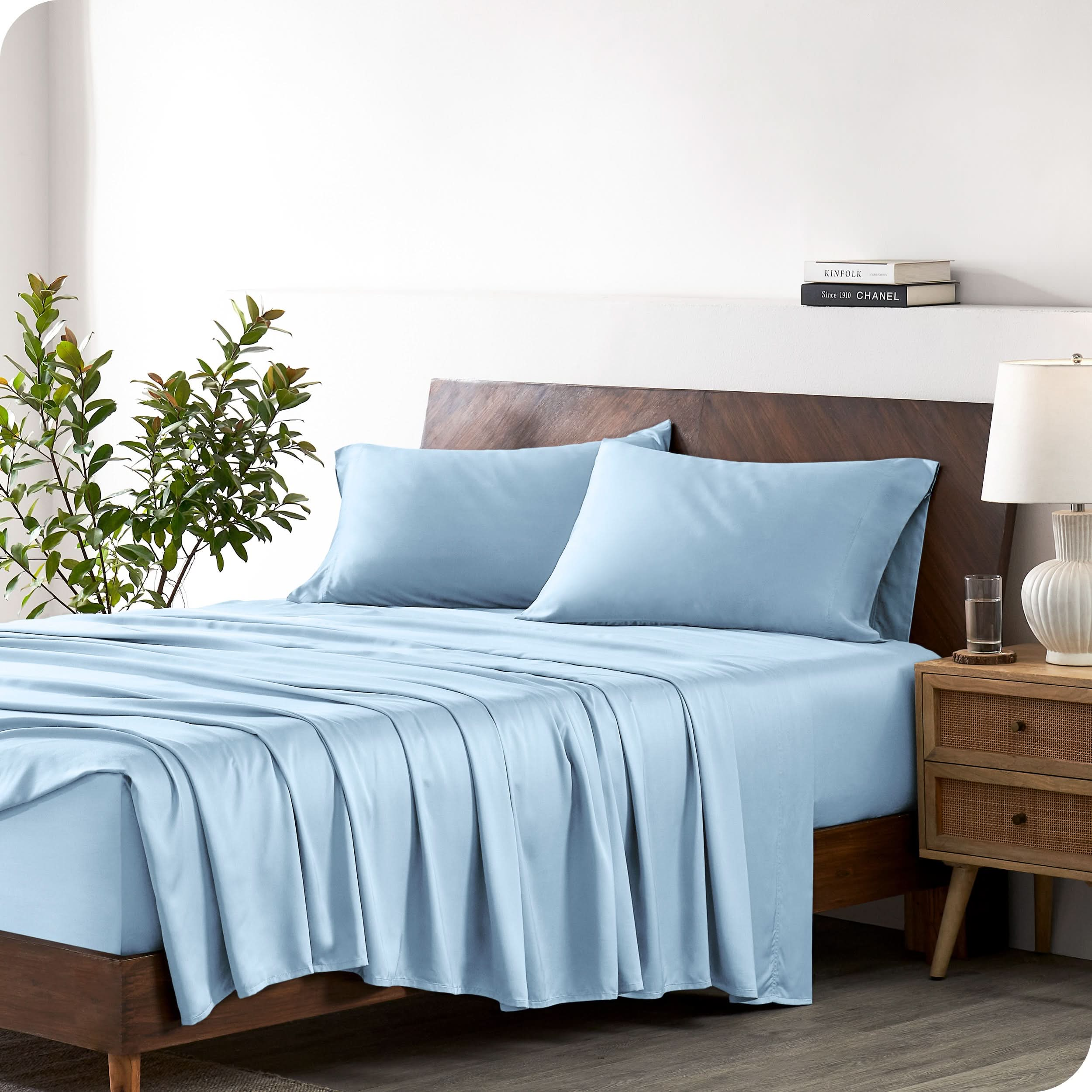 A bamboo sheet set draped over a bed with a wooden bed frame