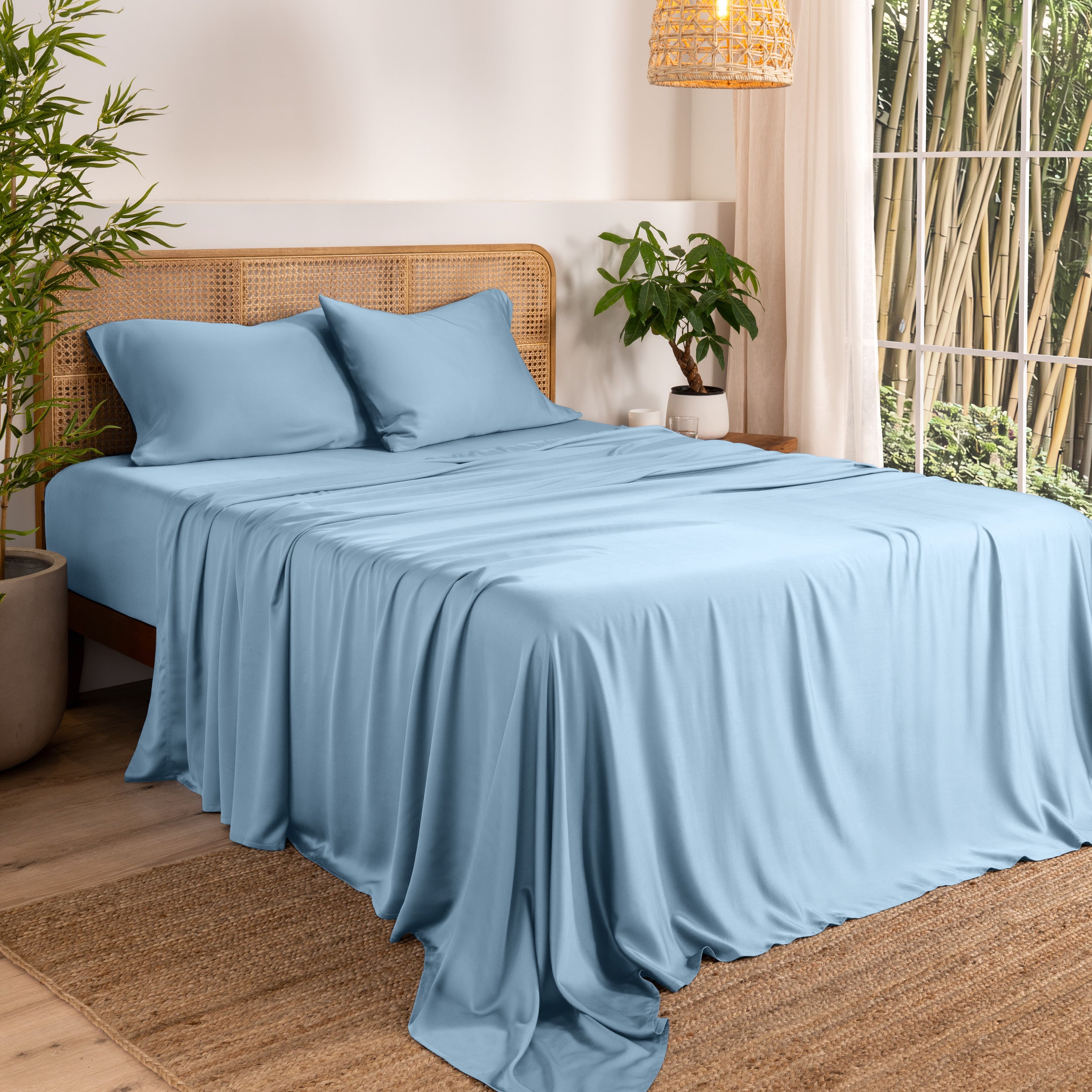 Bamboo sheets on a bed in a bedroom with plants and a lamp.