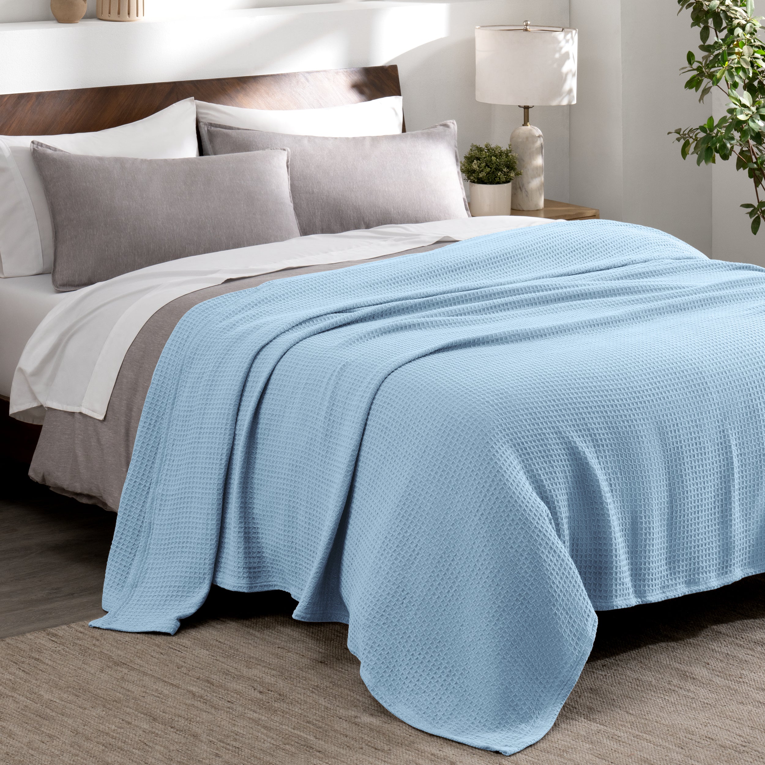 Cotton waffle blanket draped over a bed with pillows in a bedroom setting.
