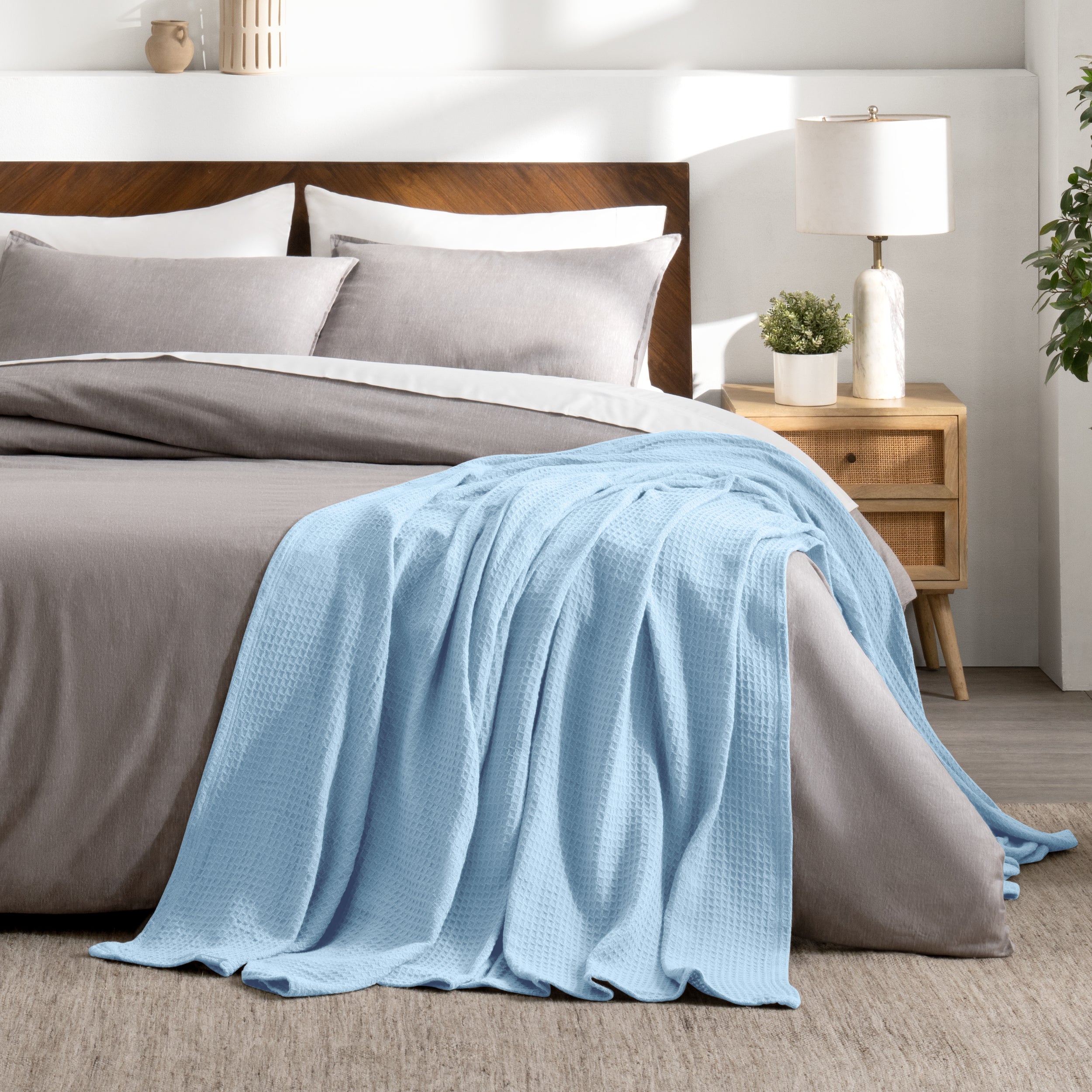 Bed with gray bedding and a throw blanket in a bedroom setting.