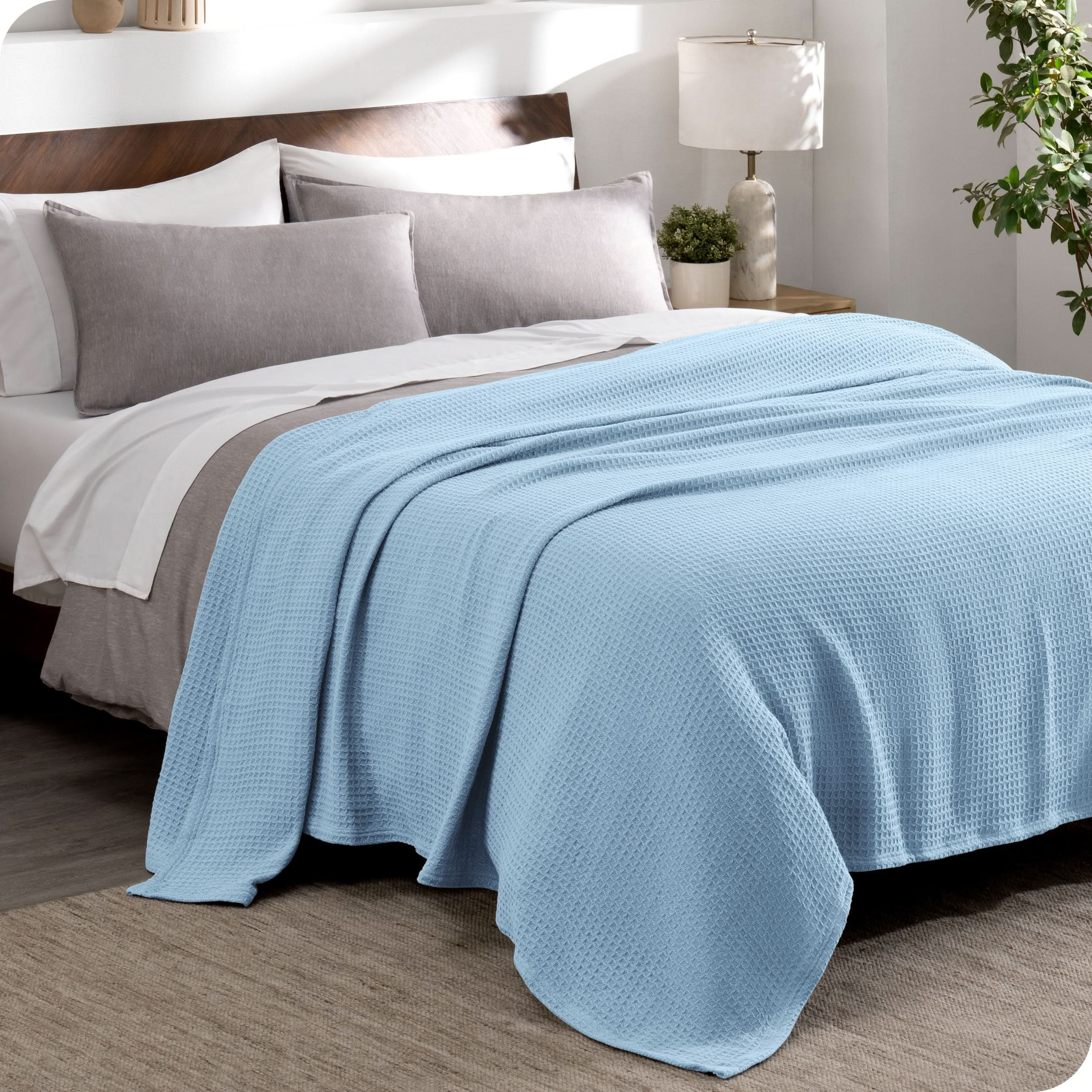 A cotton waffle blanket draped over the top of a bed made with a duvet set