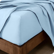 Close up of the corner of a mattress with a flannel fitted sheet and flat sheet on it