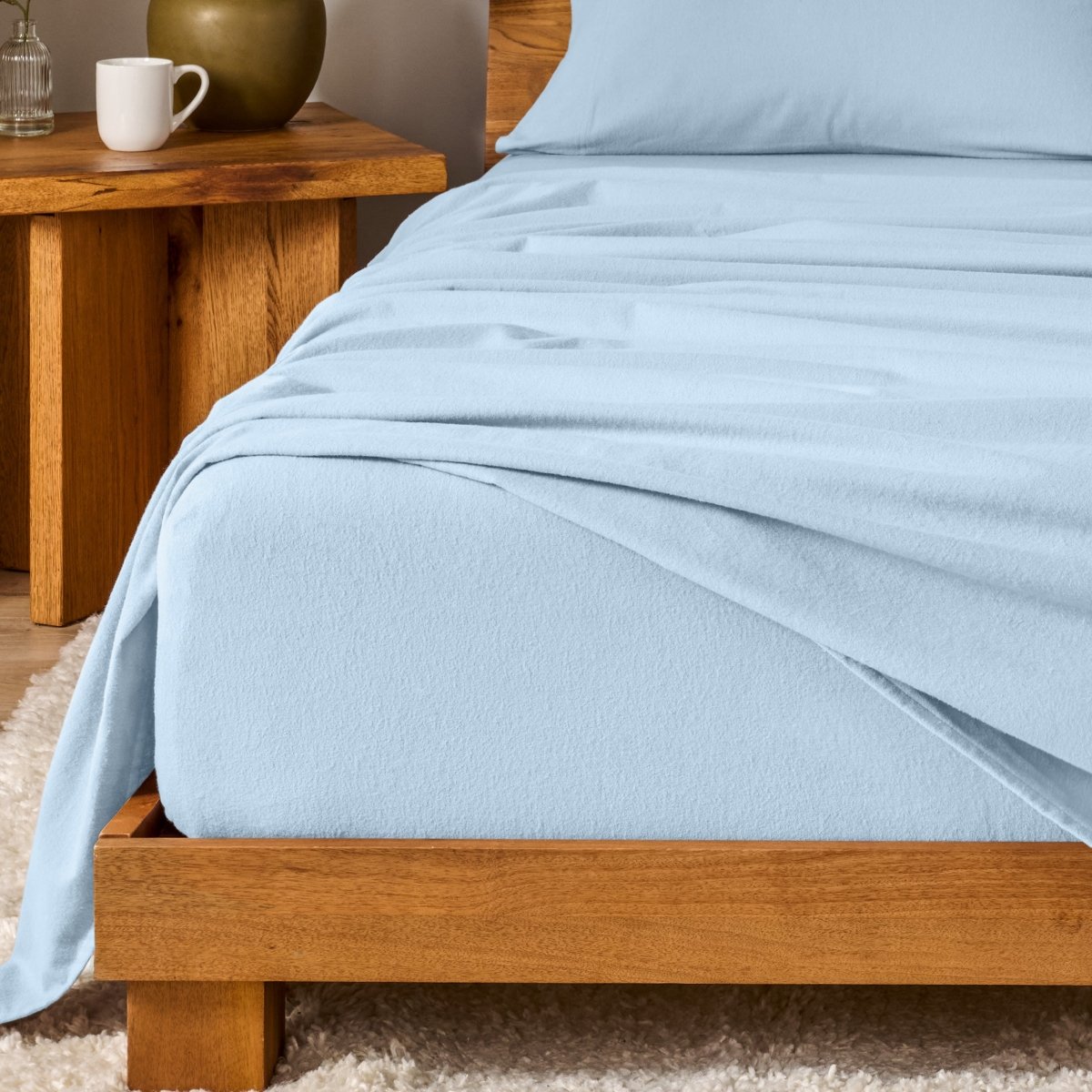 Bed with flannel bedding and wooden headboard and nightstand next to it.