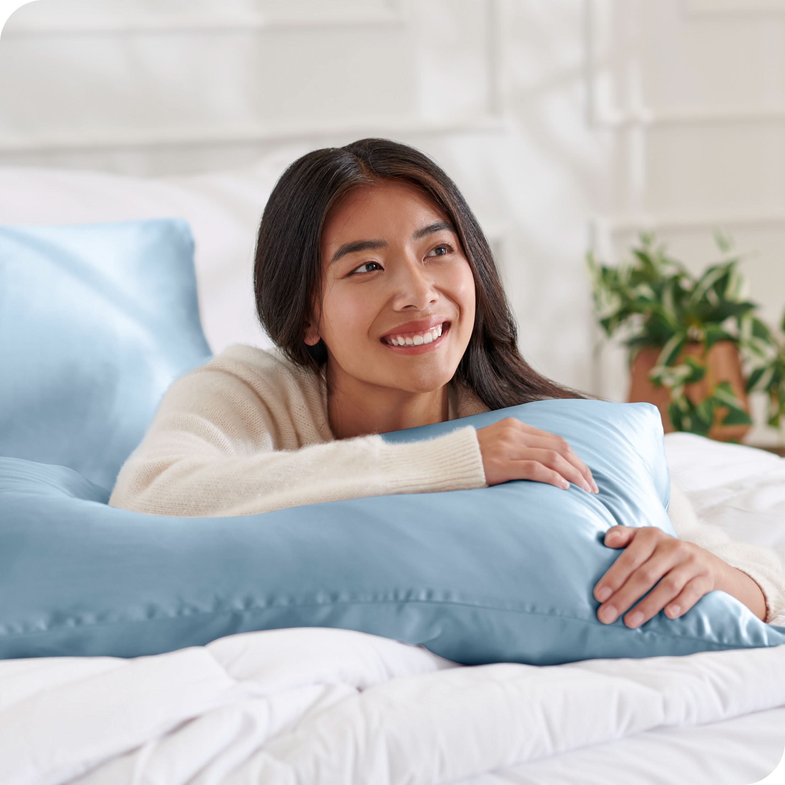 A woman on a bed with a silk pillowcase covered pillow