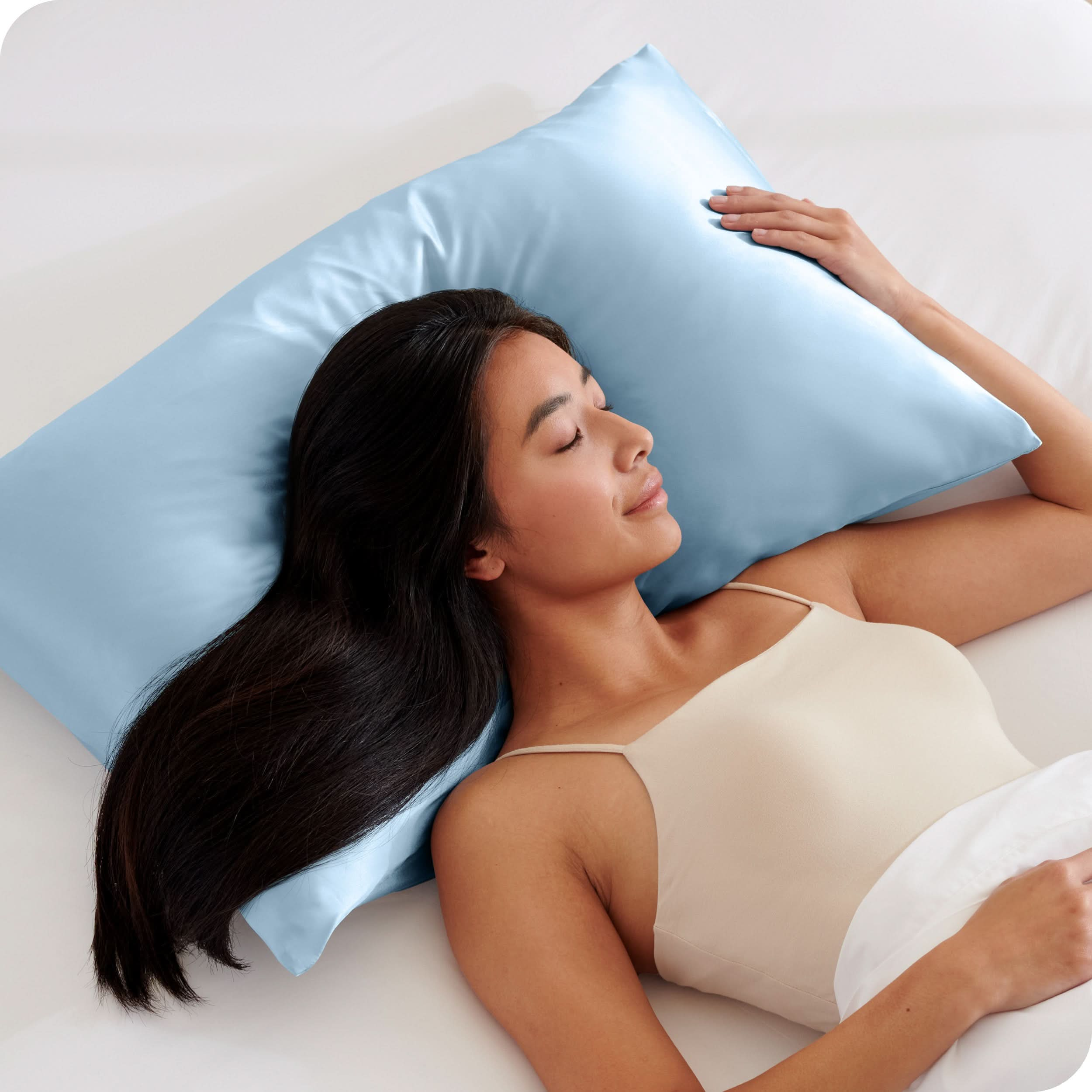 A woman is sleeping with her head on a silk pillowcase