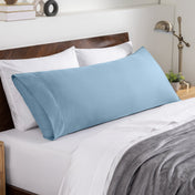Bed sheets and pillows on a neatly made bed with a wooden headboard.