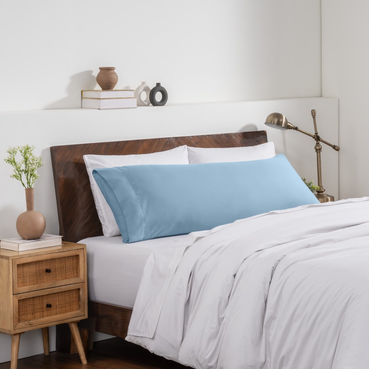 Bedroom with a wooden headboard and white bedding, featuring a nightstand and decorative items.