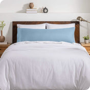A body pillow cover on a pillow on a bed with other pillows and a duvet cover