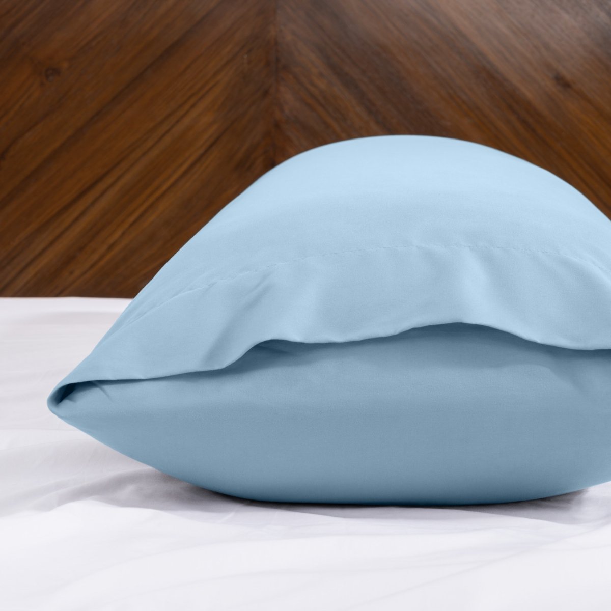 Body pillowcase with an envelope closure on a bed with a wooden headboard