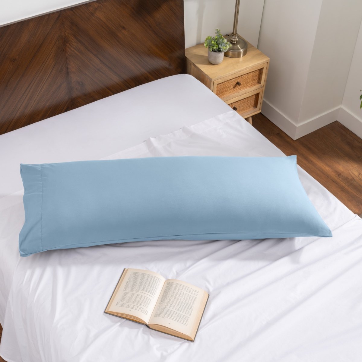 Pillowcase on a body pillow with a wooden headboard and plant in the background