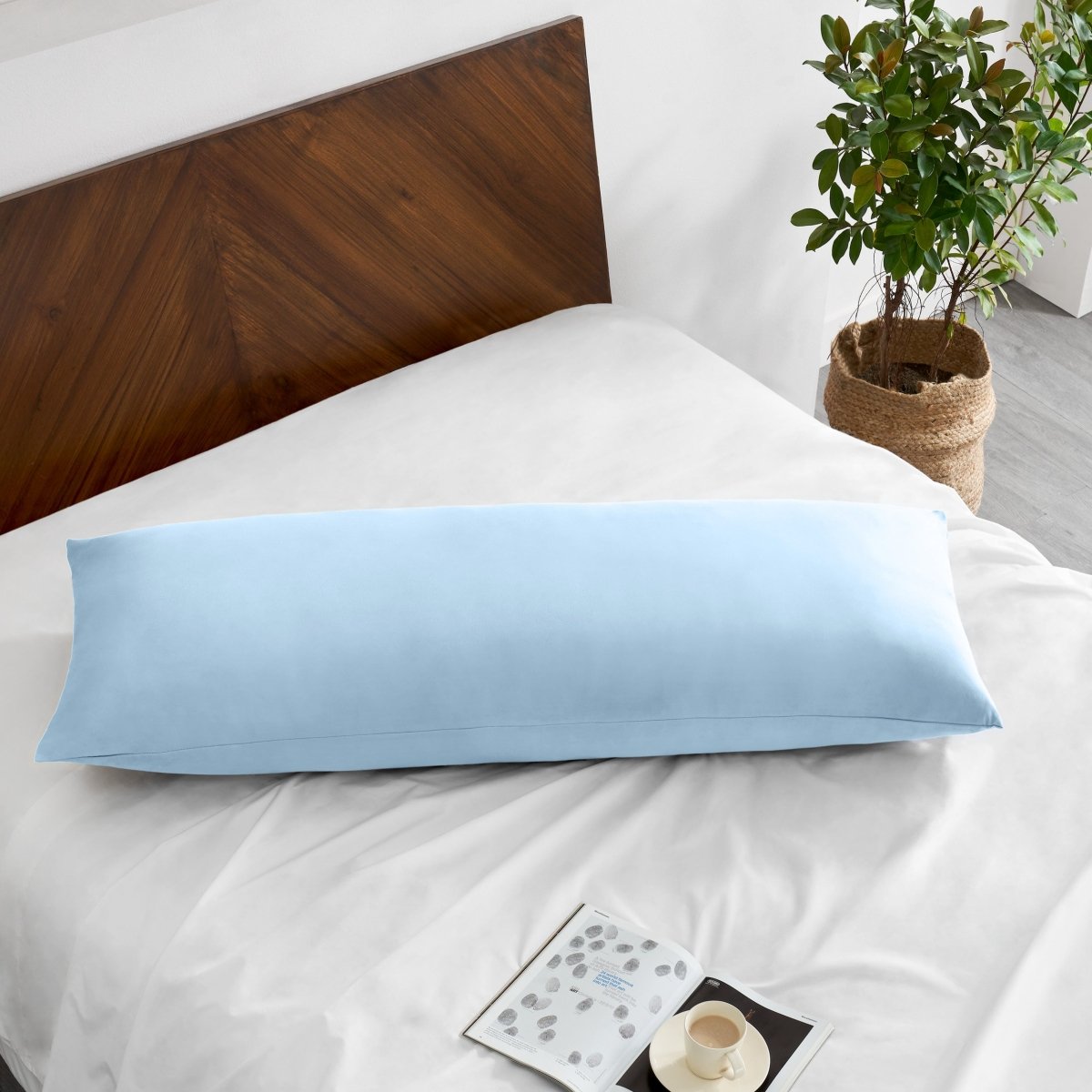 Pillowcase on a body pillow with a wooden headboard and plant in the background