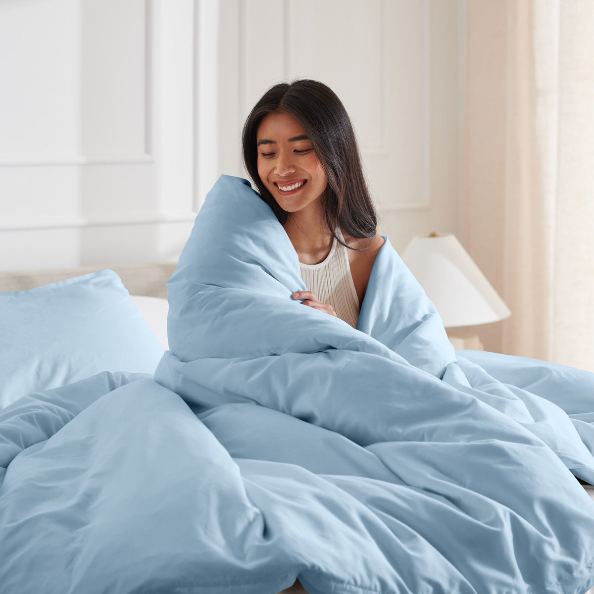 Woman smiling under duvet cover set in a bedroom setting