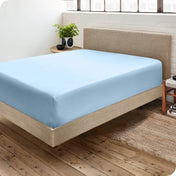 Bedroom with a microfiber fitted sheet on the mattress. A small nightstand is next to the bed with a plant and a bowl on it.
