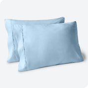 Two pillows on a white background with blue pillowcases on them