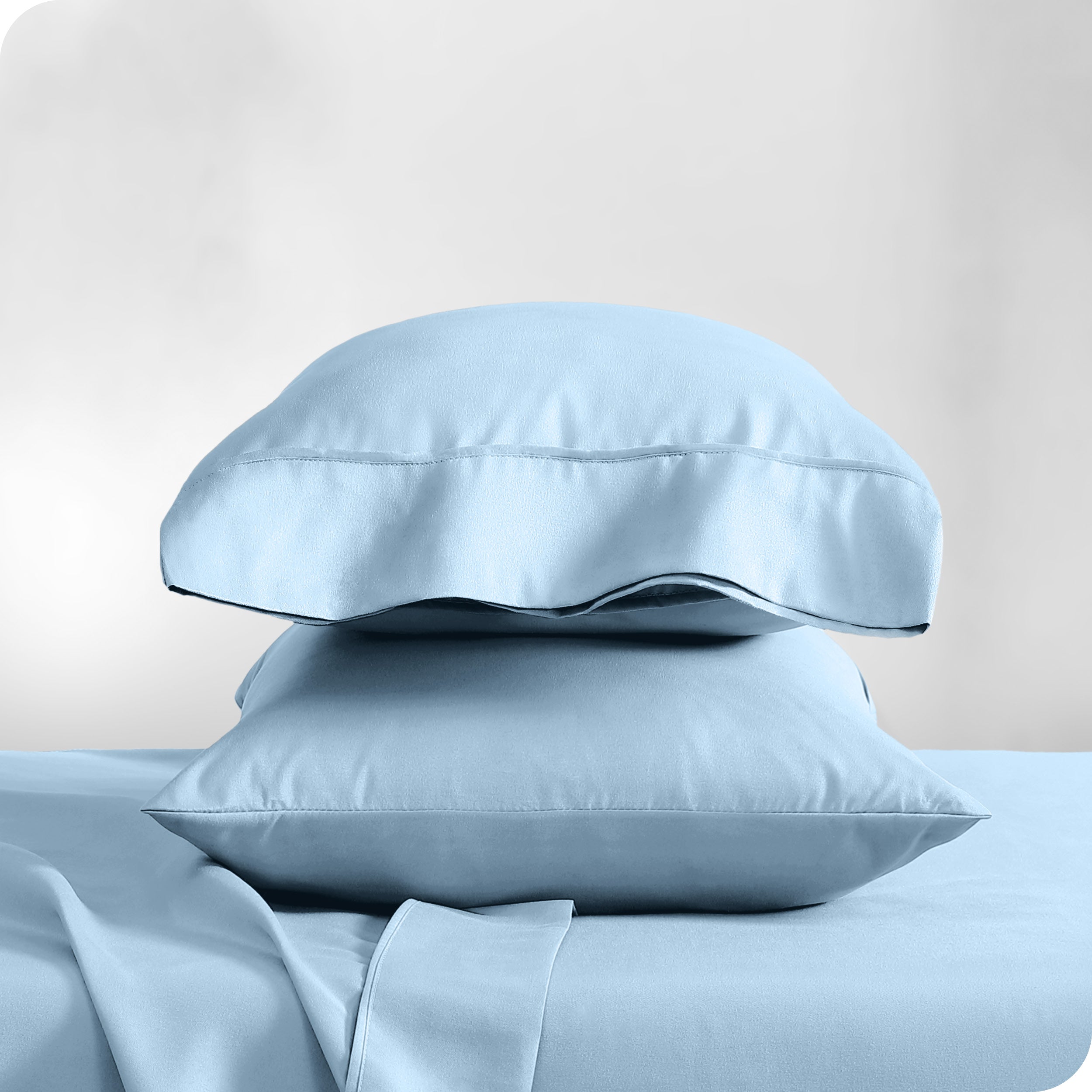 Two pillowcases on pillows stacked on a bed with matching sheets