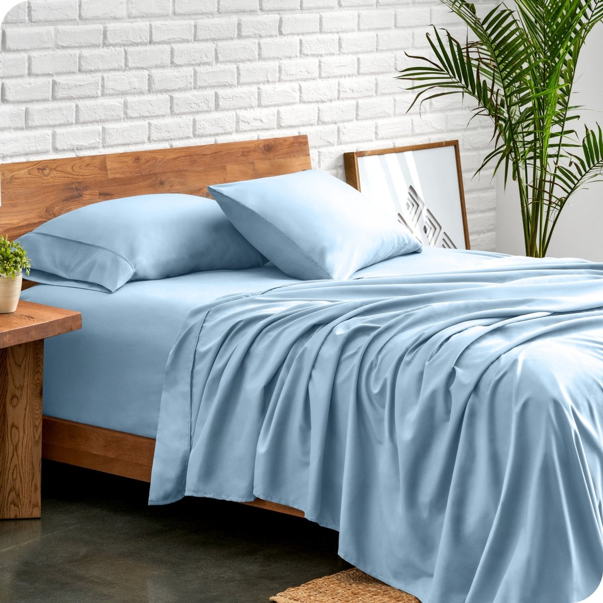 Bed with microfiber sheets against a white brick wall