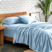 Bed with microfiber sheets against a white brick wall