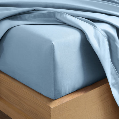 Close up of the corner of a mattress with a fitted sheet and flat sheet on it